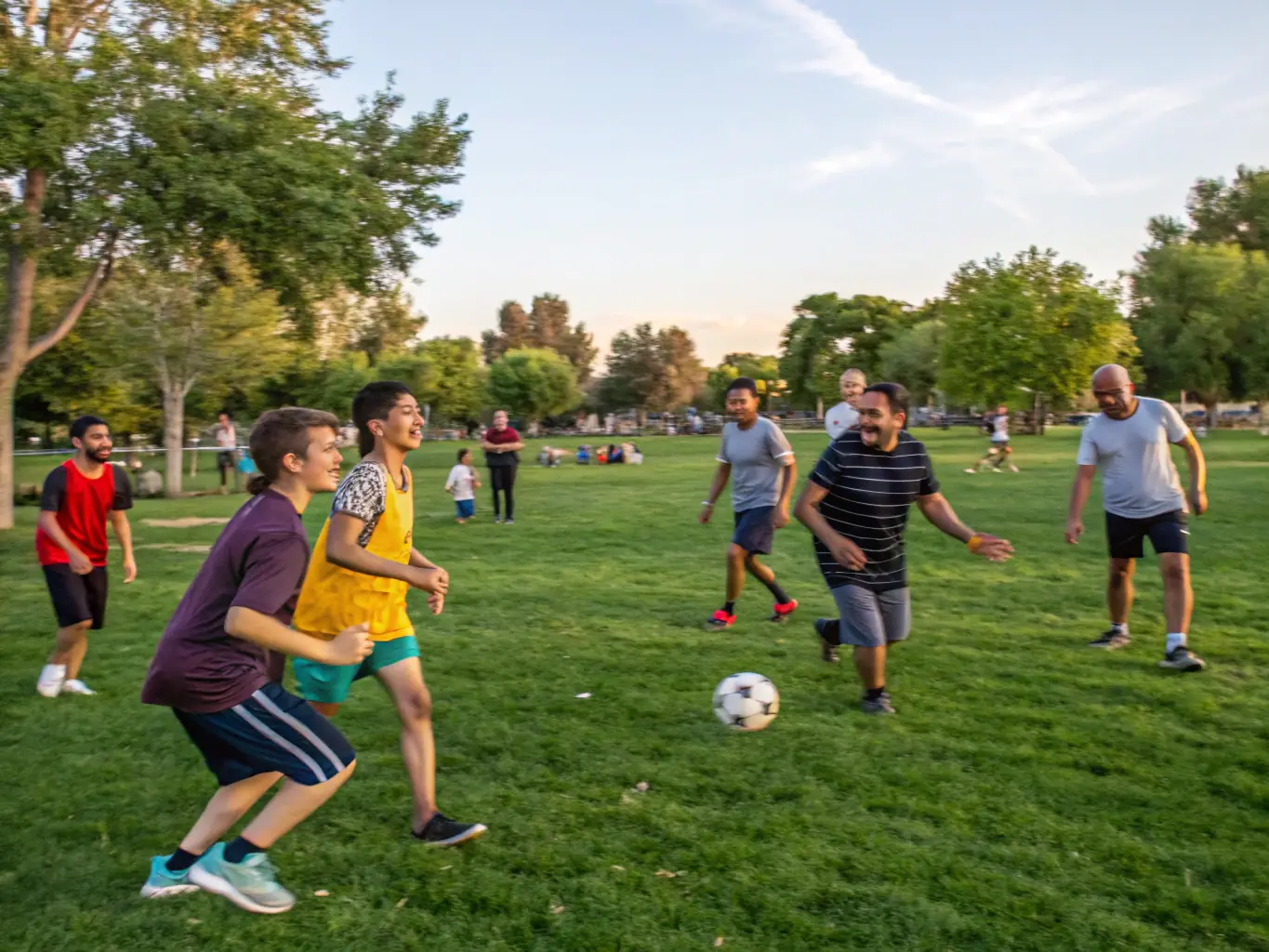 A dynamic image of children and adults playing soccer and basketball in a well-maintained sports field, showcasing active participation and community engagement.